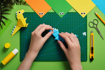 Making an origami dinosaur. Glue the eye to the head of the craft. Around us are items for paper...