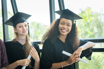 Smiling Female Graduates with Certificates, University Celebration, Happy Diverse Graduates Holding Diplomas, Two Young Women in Graduation Gowns and Caps
