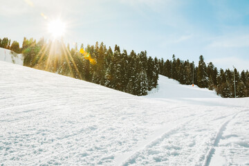 Sunlit ski slope at Hatsvali ski resort Georgia, clear blue sky, pine forest, fresh snow, empty...