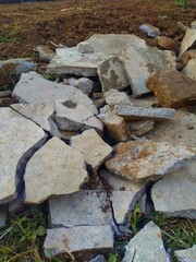 Visible are chunks of concrete and stone fragments, mixed with soil, forming a pile of textured...