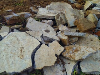 Visible are chunks of concrete and stone fragments, mixed with soil, forming a pile of textured...
