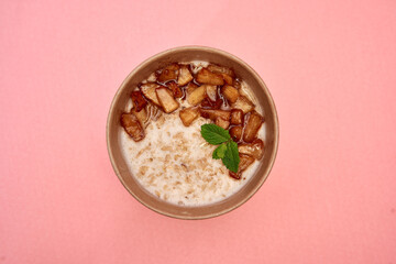 Delicious cinnamon apple oatmeal with mint on pink background