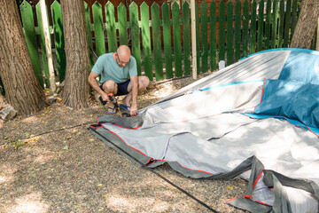 Father mounting tent for family camping in campground