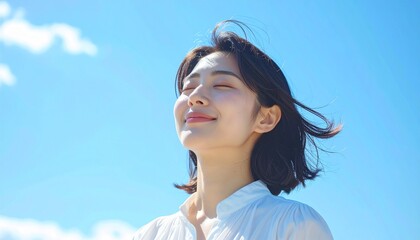 快晴の中で髪を風になびかせた若い日本人女性,A young Japanese woman with her hair blowing in the wind under a clear blue sky.