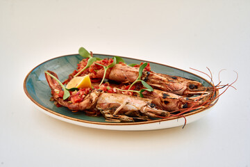 Grilled shrimp garnished with lemon and microgreens on blue plate