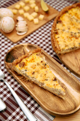 Savory mushroom cheese quiche slice on a wooden plate with checkered tablecloth