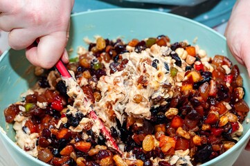 Someone stirring a bowl of fruitcake batter, preparing a holiday dessert for baking.