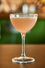 Elegant pink cocktail in coupe glass with bokeh background for upscale bar and lounge ambiance