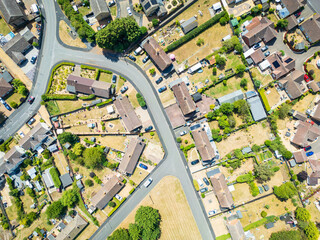 Aerial top down view of a parched lawns and vegetation seen in a town within the UK. Houses can be seen in rows along the empty street due to extreme summer weather of 2025.