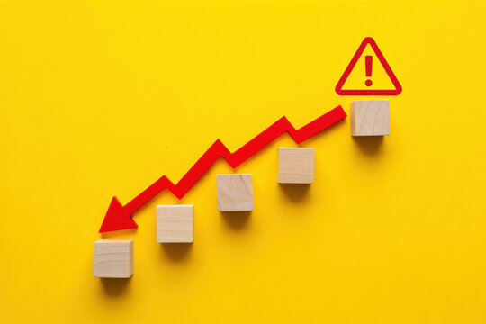 Downward Trend Arrow with Warning Sign on Yellow Background Illustrating Economic Decline and Potential Risks in Business Performance and Financial Markets