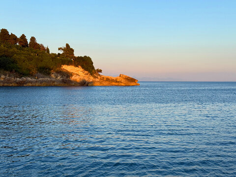 Calm blue sea and rocky coastlines at evening.