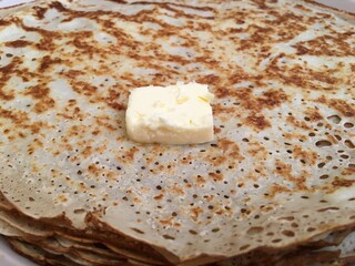 A pat of butter on a stack of freshly baked homemade pancakes. Close-up
