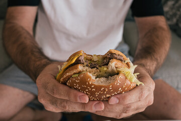 Man holding a half-eaten hamburger while camping