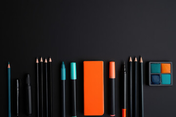 Fototapeta premium Flat lay of art supplies including pencils pens eraser and watercolor on a black surface studio shot