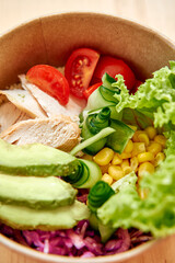 Fresh chicken salad bowl with avocado cucumber tomato and lettuce in eco-friendly container