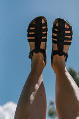 Feet in summer sandals over blue sky in the summer. Holidays vacation freedom summer traveling vibe	