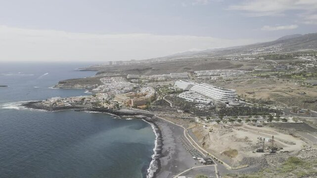Drone flies over Playa El Beril next to mega resorts in Costa Adeje, Tenerife, Canary Islands, Spain