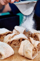 Baker dusting sugar on homemade apple cinnamon pastries