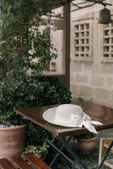 White feminine hat is on a table in a street cafe in an old european city	
