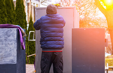 Worker in blue jacket secures a gray container during a bright morning at a construction site in...