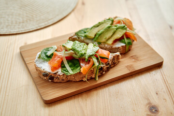 Delicious open-faced sandwich with smoked salmon, avocado, and cream cheese on rustic bread
