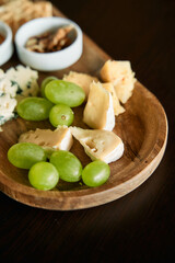 Gourmet cheese platter with grapes on wooden tray