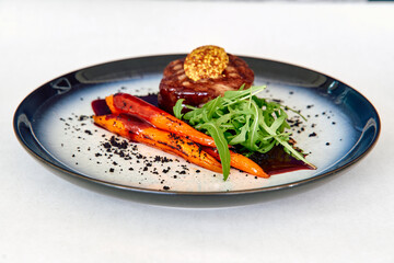 Elegant gourmet dish with beef tenderloin carrots and arugula garnish