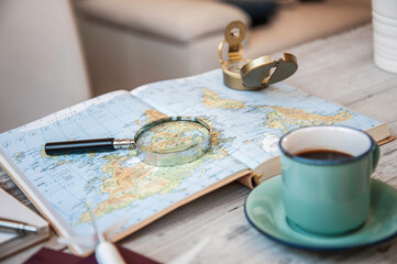 planning a new travel adventure with coffee, map, compass and magnifying glass on a wooden table. Cozy flat lay for wanderlust and trip preparation moments. Travel inspiration concept.