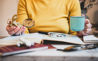woman planning a travel adventure with map, coffee mug, compass and magnifying glass at a cozy table. Preparation for a journey with wanderlust and curiosity. Travel inspiration concept.