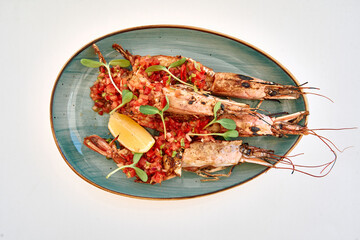 Grilled prawns with tomato salsa and lemon garnish on blue oval plate