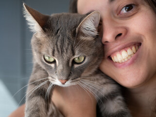 Femme souriante tenant un chat mécontent