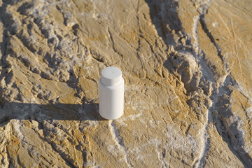 White mockup jar bottle with pills on stones by the sea. Concept of natural dietary supplements, pharmacy, natural treatment, health care.