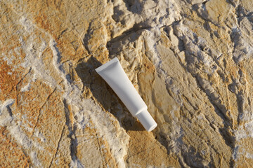 White mockup cosmetic tube of cream under the eyes on coastal stones near the sea. Ideal for...