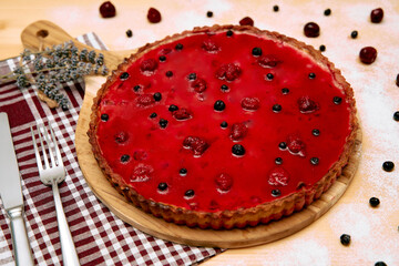 Delicious cherry and blueberry tart with vibrant red glaze on wooden board