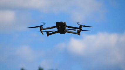 A drone hovers in a clear blue sky. Ideal for aerial photography, videography, and monitoring from...