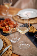 Elegant dining setup with wine glass and appetizers on woven placemats