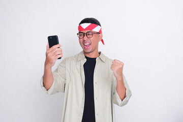Indonesian man celebrate independence day looking at his phone with enthusiastic expression