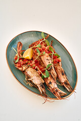 Grilled prawns with fresh tomato and herb garnish on a green plate