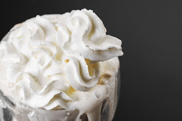 Whipped cream is squeezed out of a can onto a rotating cup of coffee on a black