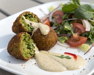 Falafel with visible inside texture and tahini sauce on clean white background for food stock use