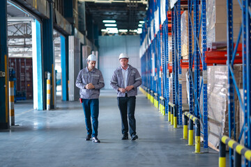 Industrial engineers walking and talking in a warehouse with high shelves full of boxes. Planning...