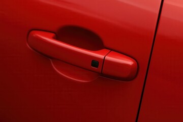 A vibrant red door handle stands out against the sleek surface of a modern vehicle, symbolizing both functionality and style
