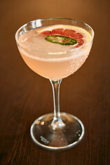Grapefruit jalapeño cocktail in elegant glass on wooden table with stylish presentation