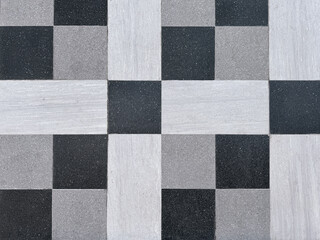 Close up of black, grey, and white tiles in random checkerboard pattern. Square shape and rectangular shape tiles. Suitable for outdoor and indoor flooring design. Seamless background texture.