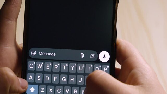 Close-up of fingers typing the XD emoticon, symbolizing laughter, on a mobile messaging app interface.