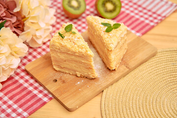 Luscious mille-feuille dessert on wooden board with kiwi and floral décor in cozy setting