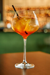 Chilled aperol spritz cocktail in elegant glass on bar table with warm ambient lighting