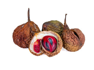 A close-up of a whole, open, dried nutmeg fruit shows the rough texture of the skin and the bright red aril that covers the seed.