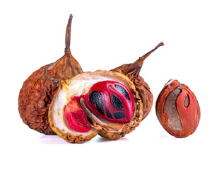 Whole nutmeg seeds with a red mace coating inside a cracked dried fruit shell, ideal for natural spice illustrations.