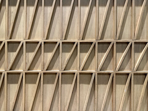 Close up of geometrical wood wall panel in slanted strips, rectangles, and triangular pattern. Modern interior design geometric screens or wall decoration. Seamless background texture.